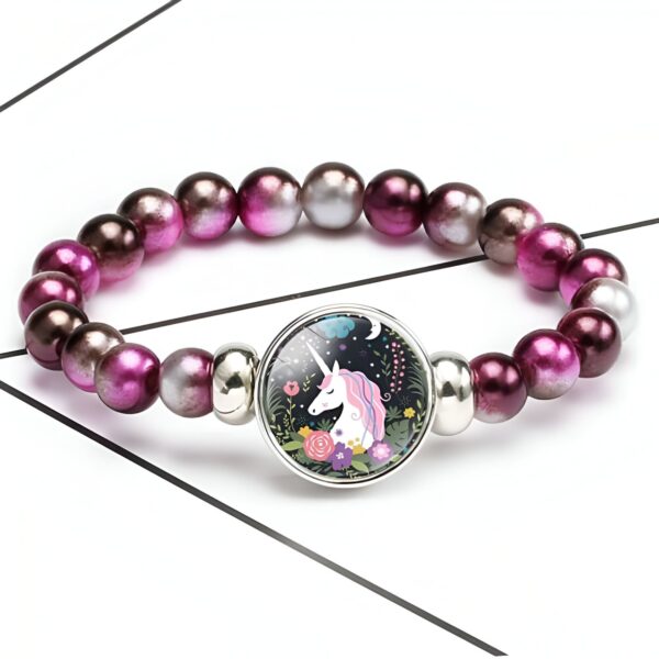 bracelet-licorne-avec-perles-multicolores-nogu-1a.jpg Bracelet élastique avec des perles roses et grises, et un pendentif rond représentant une licorne dans un jardin fleuri., 45501422698751 | Licorne Shop