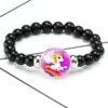 Bracelet de perles noires avec un médaillon représentant un dessin de licorne ailée sur un arc-en-ciel. Bijou fantaisie, accessoire de mode pour enfant., 45501372170495 | Licorne Shop