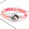 Bracelet de perles roses avec un médaillon licorne. Bijou fantaisie pour enfant avec un pendentif représentant une licorne entourée de fleurs., 45501422600447 | Licorne Shop