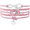 L'image représente un bracelet en cuir rose avec un pendentif en forme de cœur et un pendentif en forme de licorne. Le bracelet est orné d'un fermoir en forme d'infini avec le mot "love" écrit dessus.