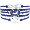 L'image représente un bracelet en cuir bleu avec un pendentif en forme de licorne. La licorne est représentée avec une crinière et une queue roses, et elle est entourée de nuages et d'étoiles. Le bracelet est également décoré de deux cœurs en métal argenté.