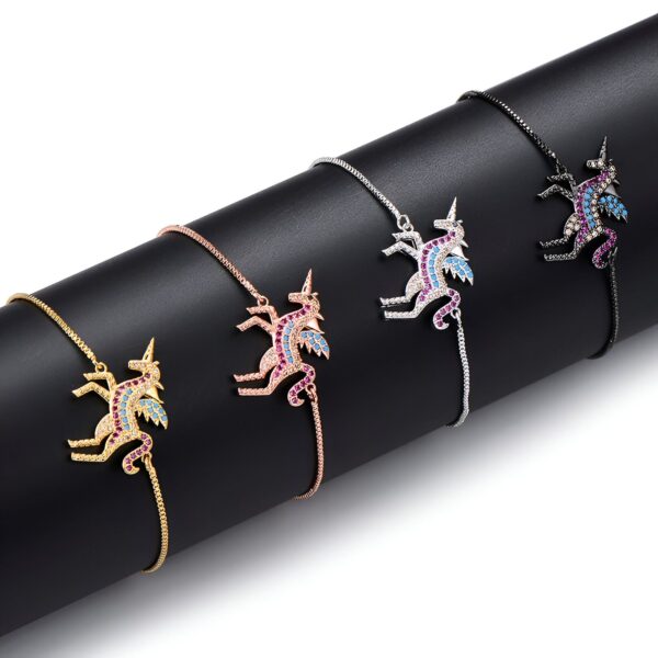 bracelet-licorne-en-zircone-cubique-6a.jpg Quatre bracelets avec des pendentifs en forme de licorne ailée. Les licornes sont serties de pierres précieuses colorées. Les bracelets sont en métal doré, argenté, or rose et noir.
