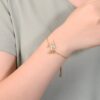 bracelet-licorne-en-zircone-cubique-7a.jpg L'image montre un bracelet en or avec un pendentif licorne. La licorne est sertie de pierres précieuses multicolores. Le bracelet est porté par une femme.
