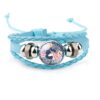 bracelet-licorne-enfant-tresse-2a.jpg Le bracelet est en cuir tressé bleu avec un fermoir en acier inoxydable. Il est décoré d'une perle en verre avec une image d'une licorne blanche avec des fleurs roses et bleues.