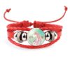 bracelet-licorne-enfant-tresse-3a.jpg Un bracelet en cuir rouge avec un pendentif en verre rond. Le pendentif représente une licorne blanche avec une crinière et une queue roses. La licorne est entourée de fleurs et de coeurs.