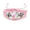 bracelet-licorne-enfant-tresse-5a.jpg Un bracelet en cuir rose avec un pendentif en verre rond qui représente une licorne blanche avec une crinière et une queue roses. La licorne est entourée de fleurs et de feuilles vertes.