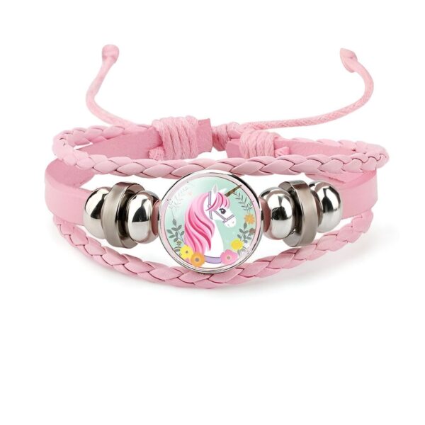 bracelet-licorne-enfant-tresse-5a.jpg Un bracelet en cuir rose avec un pendentif en verre rond qui représente une licorne blanche avec une crinière et une queue roses. La licorne est entourée de fleurs et de feuilles vertes.
