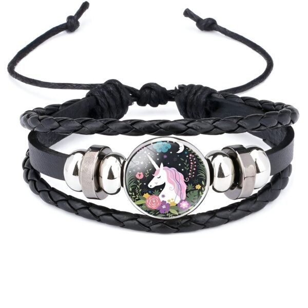 bracelet-licorne-enfant-tresse-7a.jpg Le bracelet en cuir noir tressé est orné d'une breloque en verre ronde. Le motif de la breloque représente une licorne blanche avec une crinière et une queue roses et violettes. La licorne se tient dans un pré fleuri avec des fleurs roses, violettes et bleues. Le fond est constitué d'un ciel étoilé avec une lune et des nuages.
