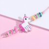 Un bracelet avec une breloque en forme de licorne. La licorne est blanche avec une crinière et une queue roses. Elle a une corne dorée et des yeux bleus. Le bracelet est en fil rose et est décoré de perles colorées.