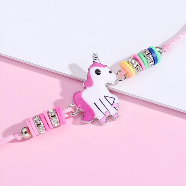 Un bracelet avec une breloque en forme de licorne. La licorne est blanche avec une crinière et une queue roses. Elle a une corne dorée et des yeux bleus. Le bracelet est en fil rose et est décoré de perles colorées.