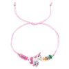Un bracelet rose avec une breloque licorne blanche et des perles colorées.