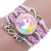 bracelet-licorne-tresse-fille-1a.jpg Le bracelet est en cuir tressé rose avec un fermoir en forme d'infini. Il y a un médaillon rond en verre avec une image d'une licorne blanche avec une crinière et une queue arc-en-ciel. La licorne a une fleur rose dans les cheveux et est entourée de coeurs et d'étoiles. Il y a aussi le mot "love" en métal argenté sur le bracelet.