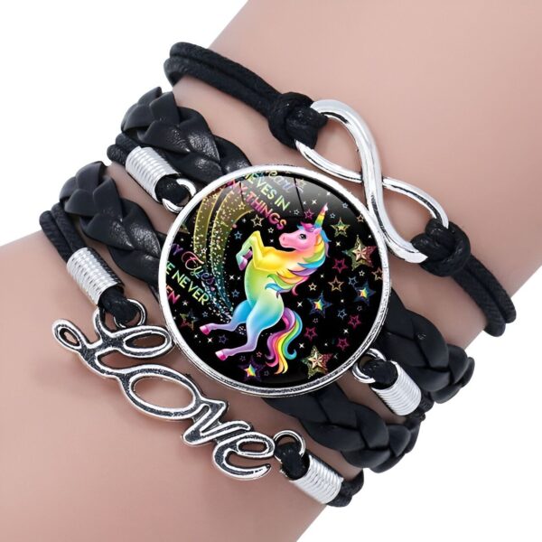 bracelet-licorne-tresse-fille-2a.jpg Le bracelet est en cuir noir et comporte une breloque en forme de licorne. La licorne est représentée avec une crinière et une queue arc-en-ciel. Le bracelet est également orné de étoiles et de lunes.