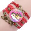 bracelet-licorne-tresse-fille-7a.jpg L'image montre un bracelet en cuir rouge avec un pendentif en forme de licorne endormie sur un nuage. Le bracelet est également décoré de deux breloques en forme de cœur et d'une breloque en forme d'infini.