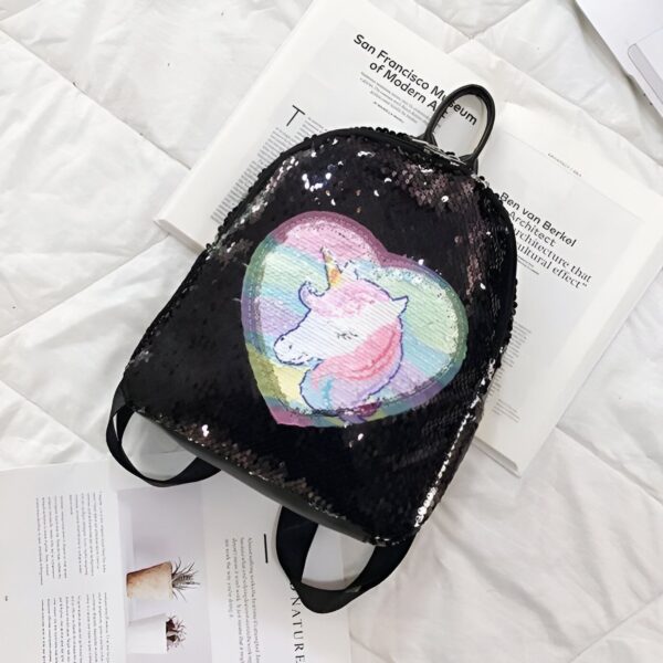 cartable-licorne-amour-noir-1a.jpg Un sac à dos noir à sequins avec un motif de licorne arc-en-ciel.