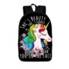 Le cartable noir a une image de licorne blanche avec une crinière arc-en-ciel et des fleurs roses et bleues. Le texte sur le cartable dit "She's beauty, she's grace, she'll kick you in the face".