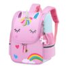 Le cartable est rose avec une image de licorne. La licorne a une corne argentée, des yeux bleus et une crinière arc-en-ciel. Le cartable a également une poignée et des bretelles roses. Il y a un porte-clés en forme de licorne sur le côté du cartable.