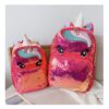 cartable-licorne-paillette-rouge-2a.jpg Deux sacs à dos à paillettes roses en forme de licorne sont placés sur une chaise. Les sacs à dos ont des yeux et une corne de licorne.