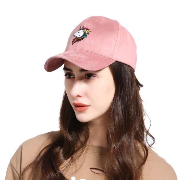 casquette-licorne-adulte-rose-1a.jpg Une jeune femme porte une casquette rose en daim avec une broderie d'une licorne. La licorne a une crinière arc-en-ciel et un œil fermé. La femme a les cheveux longs et bruns et porte un maquillage léger. Elle regarde vers le bas.