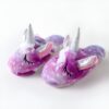 Une paire de pantoufles licorne violettes et blanches avec une corne et des oreilles de licorne.