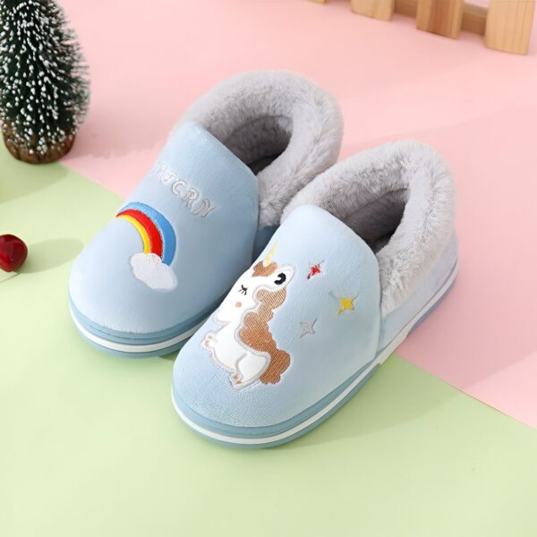 chausson-licorne-fille-montant-bleu-1a-1.jpg Une paire de pantoufles licorne bleue avec une corne et une crinière arc-en-ciel.