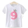 T-shirt blanc pour enfant, décoré d'un grand chiffre 9 rose orné d'un motif licorne avec des fleurs, suspendu à un cintre en bois. Idéal pour un anniversaire de 9 ans., 45502332141823,45502332174591,45502332207359,45502332240127,45502332272895,45502332305663,45502332338431,45502332371199 | Licorne Shop