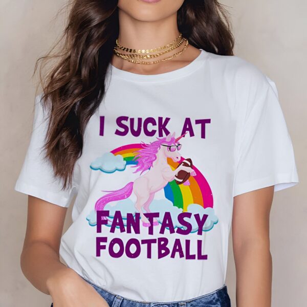 T-shirt blanc avec un motif humoristique : une licorne rose portant des lunettes de soleil, devant un arc-en-ciel, tenant un ballon de football américain. Le texte imprimé dit "I suck at fantasy football"., 45502315036927,45502315069695,45502315102463,45502315135231,45502315167999,45502315200767,45502315233535,45502315266303 | Licorne Shop