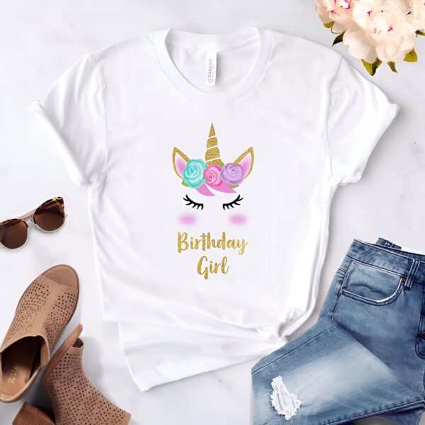 chemise-licorne-de-fete-1a.jpg T-shirt blanc avec motif de licorne orné de fleurs et l'inscription "Birthday Girl" en doré, accompagné de lunettes de soleil, chaussures et jean bleu., 45502315299071,45502315331839,45502315364607,45502315397375,45502315430143,45502315462911,45502315495679,45502315528447 | Licorne Shop