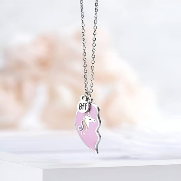 Deux moitiés d'un cœur en émail rose avec des détails en argent et un pendentif en forme de licorne arc-en-ciel. Le texte "BFF" est gravé sur une plaque en métal.