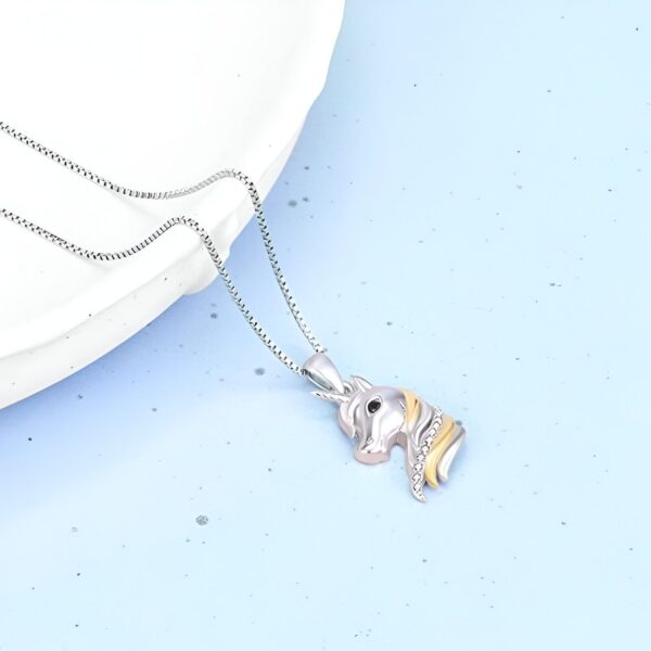 collier-licorne-anniversaire-3a.jpg Un pendentif en forme de tête de licorne en argent avec une crinière en or et des détails en zircone cubique. La chaîne est en argent et mesure 45 cm de long.
