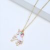 collier-licorne-fille-3a.jpg L'image représente un collier avec un pendentif en forme de licorne. La licorne est blanche avec une crinière et une queue arc-en-ciel. Le collier est en métal doré.