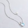 collier-licorne-fille-elegance-4a.jpg L'image représente un collier avec un pendentif en forme de licorne et un pendentif en forme d'arc-en-ciel. La licorne est blanche et a une crinière et une queue arc-en-ciel. L'arc-en-ciel est coloré et a les couleurs suivantes : rouge, orange, jaune, vert, bleu, indigo et violet. Le collier est en argent et la chaîne est fine et délicate.