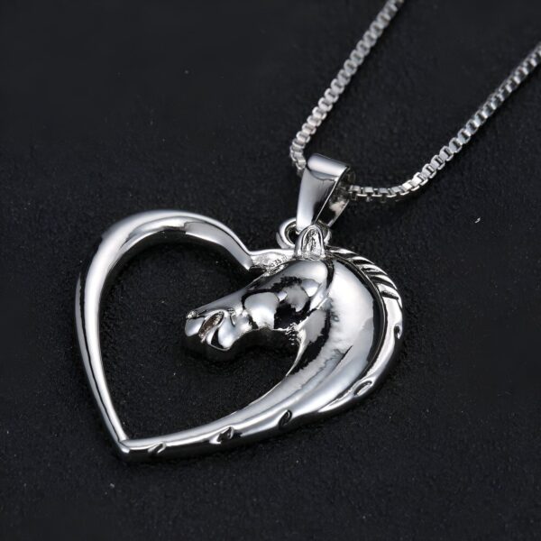 Un pendentif en forme de cœur en argent avec un cheval à l'intérieur.