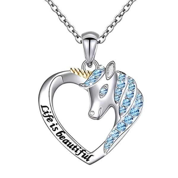 collier-licorne-la-vie-est-belle-1a.jpg L'image représente un pendentif en forme de cœur avec une licorne. La licorne est sertie de cristaux bleus et le cœur est en argent. Le pendentif est suspendu à une chaîne en argent.