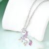 collier-licorne-princesse-2a.jpg L'image représente un collier avec un pendentif en forme de licorne. La licorne est blanche avec une crinière et une queue roses et bleues. Elle a une corne dorée et un collier avec des pierres précieuses roses et bleues. Le collier est en argent.