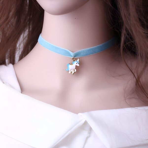 Un collier de velours bleu avec un pendentif licorne en métal doré. La licorne est blanche avec une crinière et une queue bleues.