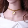 Une jeune femme porte un collier en velours jaune avec un pendentif licorne en métal doré. La licorne est blanche avec une crinière et une queue jaunes.