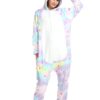 Une femme porte une combinaison pyjama licorne arc-en-ciel avec des étoiles blanches. La combinaison est à capuche et a des pieds intégrés. La femme est debout et sourit.