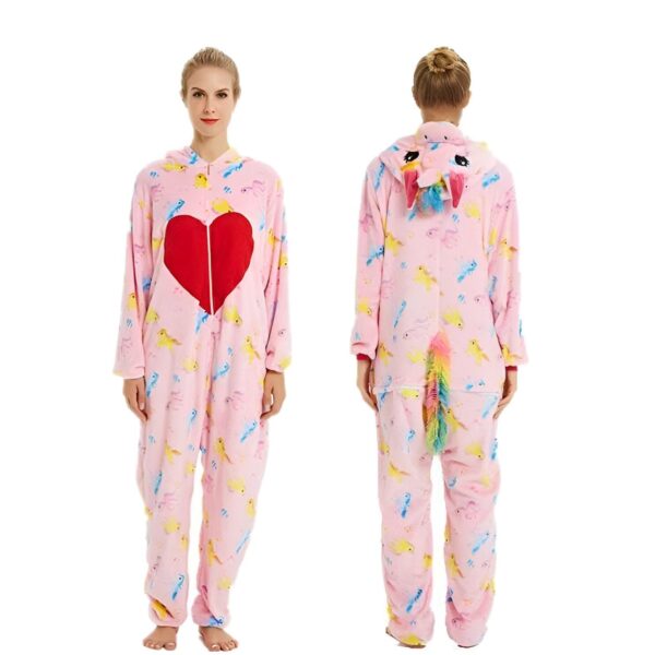 combinaison-licorne-femme-coeur-rouge-1a.jpg Une femme porte une combinaison pyjama licorne rose avec une capuche et une poche en forme de cœur rouge sur le devant. La combinaison est imprimée de motifs d'oiseaux et de licornes.