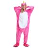 Une femme porte une combinaison pyjama licorne rose avec une capuche et des pieds en forme de pattes de licorne.