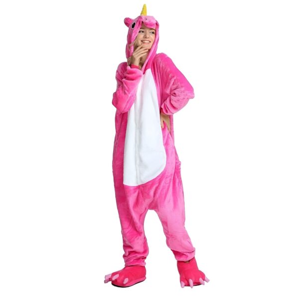 Une femme porte un pyjama licorne rose avec une capuche et des pieds en forme de pattes de licorne.