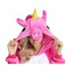 Une femme porte une combinaison pyjama licorne rose et blanche. La combinaison est à capuche avec une corne de licorne jaune sur le dessus de la tête. La femme a les yeux bleus et les cheveux blonds. Elle sourit et regarde l'appareil photo.