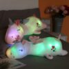 coussin-lumineux-licorne-veilleuse-1a.jpg Deux peluches licornes lumineuses reposent sur un lit. Elles sont colorées et ont des motifs de cœurs. Des fleurs décorent l'arrière-plan., 45501066281215 | Licorne Shop