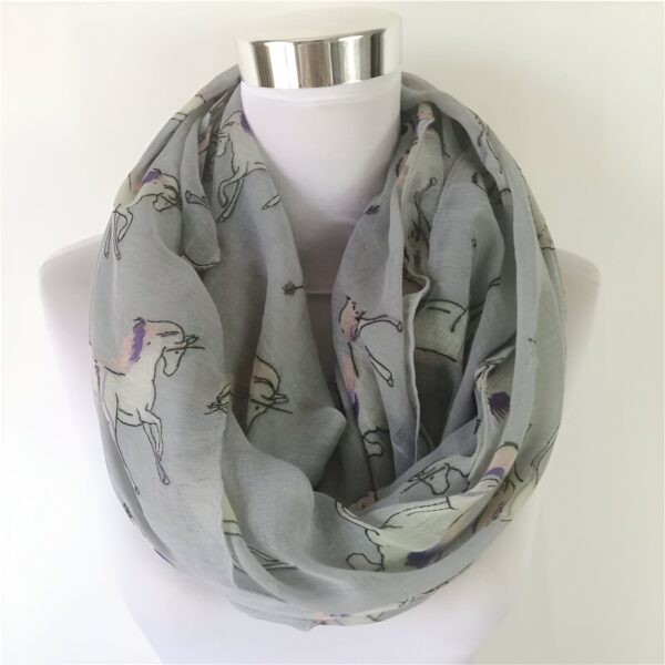 echarpe-tour-de-cou-licorne-grise-chaude-1a.jpg Écharpe tube gris clair à motifs de licornes stylisées, présentée sur un mannequin blanc. Accessoire de mode tendance., 45502092017919 | Licorne Shop