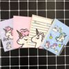 Quatre petits carnets avec des couvertures à motifs licorne de différentes couleurs (violet, rose, beige et bleu) sont disposés sur un fond à carreaux noirs et blancs. Un stylo est visible à côté du carnet bleu., 45501153083647 | Licorne Shop