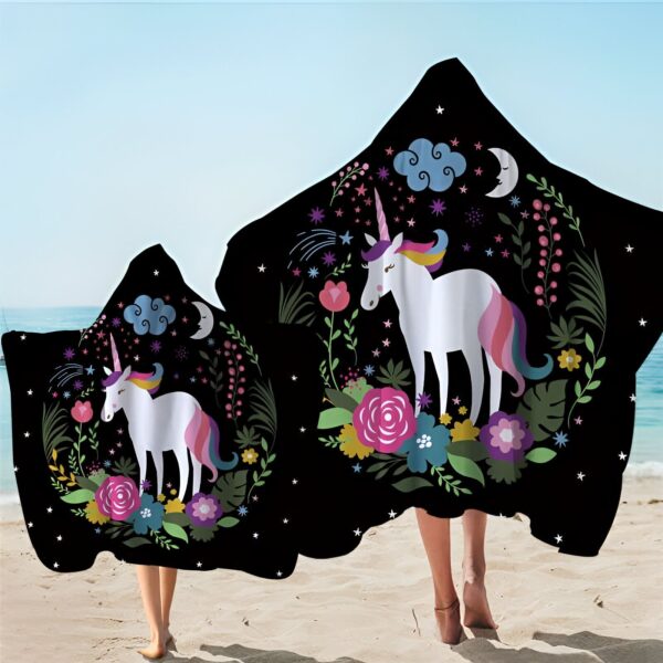 Deux personnes sur la plage portant des serviettes à capuche noires avec un motif de licorne blanche, des fleurs colorées, des étoiles, un croissant de lune et des nuages. Idéal pour les enfants et les adultes après la baignade., 45501226090751 | Licorne Shop