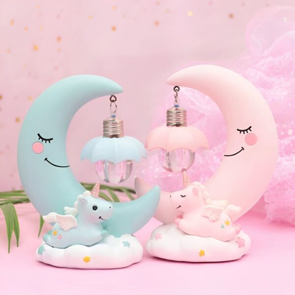 lampe-de-chevet-fille-licorne-2a.jpg Deux veilleuses en forme de croissant de lune, l'une rose et l'autre bleue. Sur chaque lune est assis un bébé licorne de la couleur opposée. Les licornes ont des ailes et sont allongées, la tête posée sur leurs pattes avant. Les lunes ont des yeux et sourient.