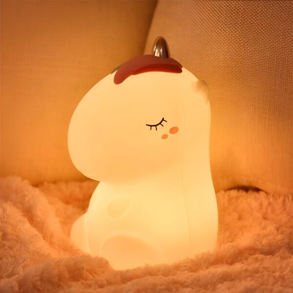 lampe-licorne-led-rechargeable-sans-fil-1a.jpg Une veilleuse en forme de licorne blanche avec une corne rose et des ailes. Elle est posée sur un tapis rose.