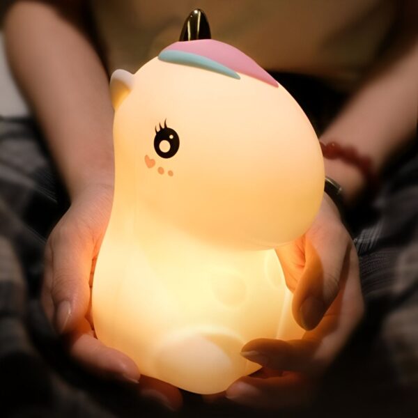 lampe-licorne-rose-led-1a.jpg Une veilleuse licorne en forme de dessin animé, avec une corne dorée, une crinière et une queue arc-en-ciel. La veilleuse est en silicone souple et émet une lumière douce et apaisante. Elle est parfaite pour les enfants qui ont peur du noir ou pour les adultes qui veulent créer une ambiance relaxante.