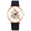 montre-licorne-elegance-noir-1a.jpg Une montre analogique à quartz avec un bracelet en cuir noir et un cadran rond en métal doré. Le cadran représente une licorne blanche avec une crinière et une queue roses, entourée de fleurs et de feuillage.